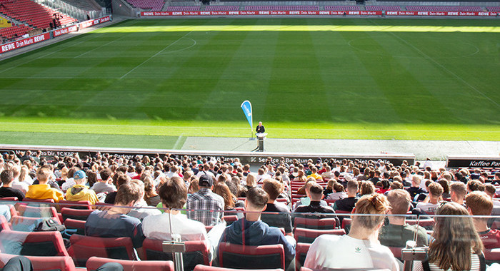 Studierende auf der Tribüne im Fußballstadion Studierende auf der Tribüne im Fußballstadion