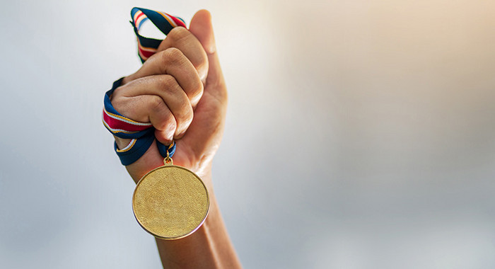 Hand hält Medaille an einem Band hoch