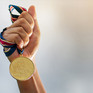 Hand hält Medaille an einem Band hoch