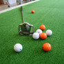 Golfbälle und Schläger auf grünem Grund